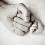 Man's hand fist bumping baby's hand