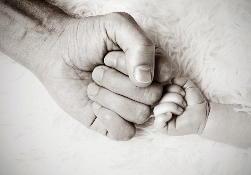 Man's hand fist bumping baby's hand